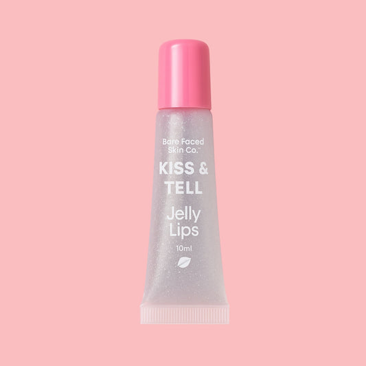 Crystal Clear™ Kiss & Tell Jelly Lips lip gloss tube, clear shimmer gloss in a pink squeeze tube with pink cap, displayed on a soft pink background.